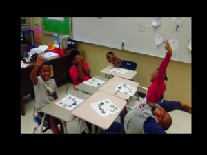 Kids laughing and playing with cookies in classroom.